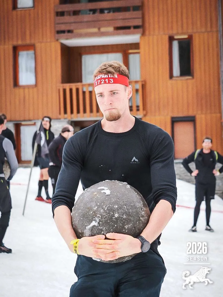 Le coach COACHDIM portant une lourde balle lestée pendant une Spartan Race