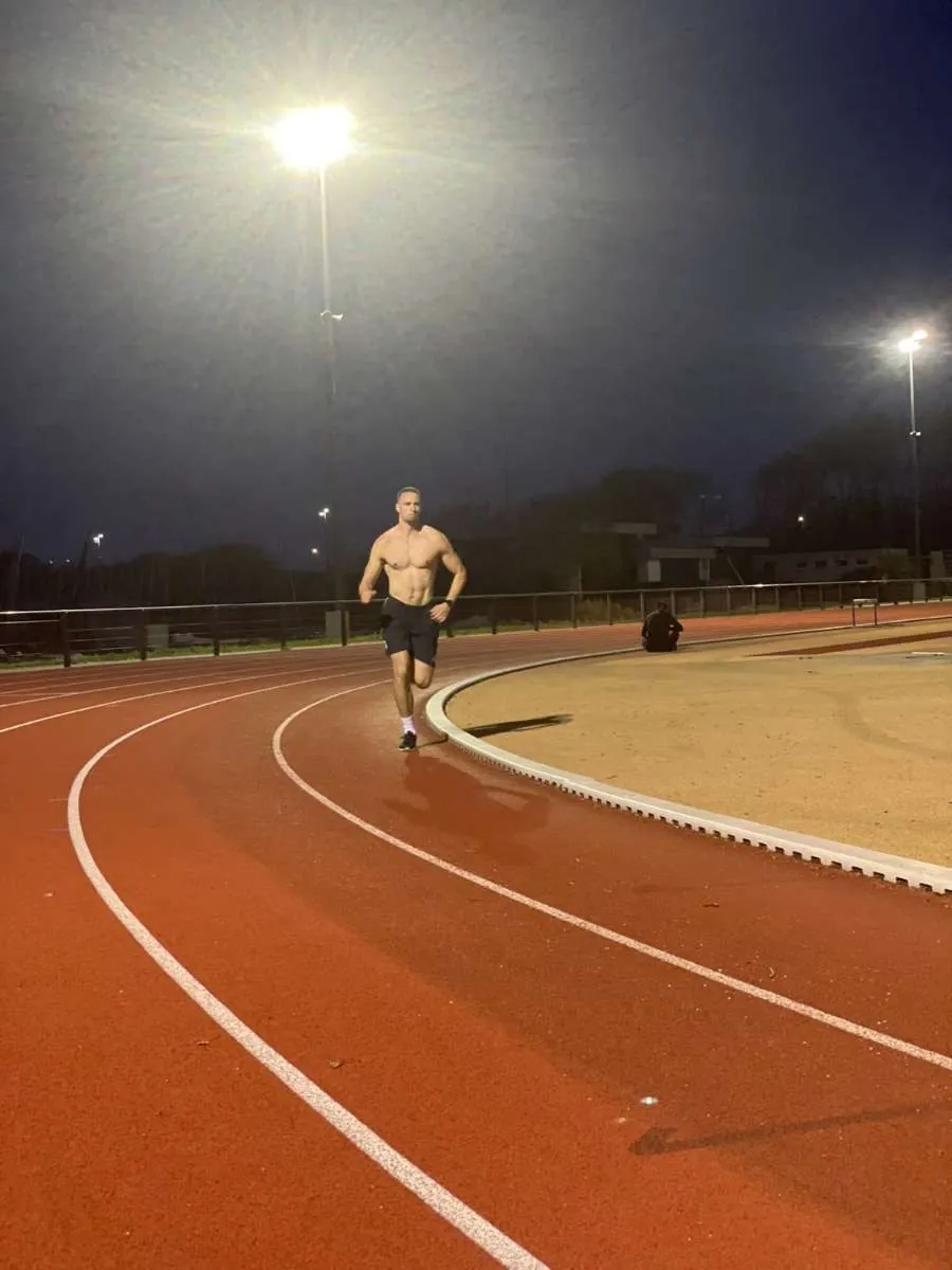 Le coach en séance de course à pied sur piste d'athlétisme, de nuit